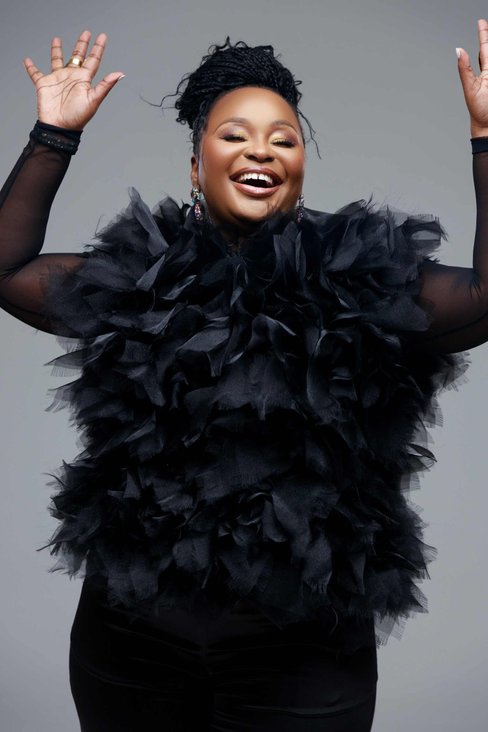 Xolly raising her hand in a black studio portrait
