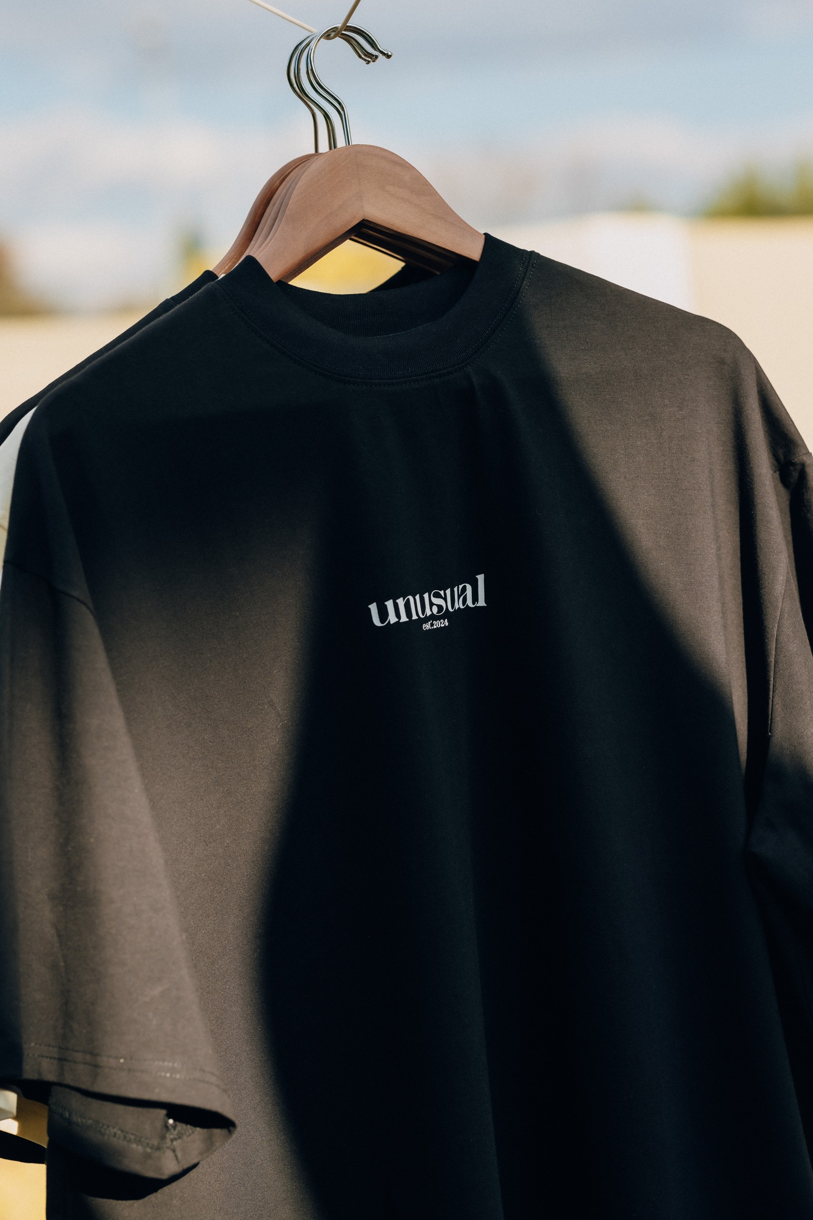 A black Unusual T-shirt on a hanger