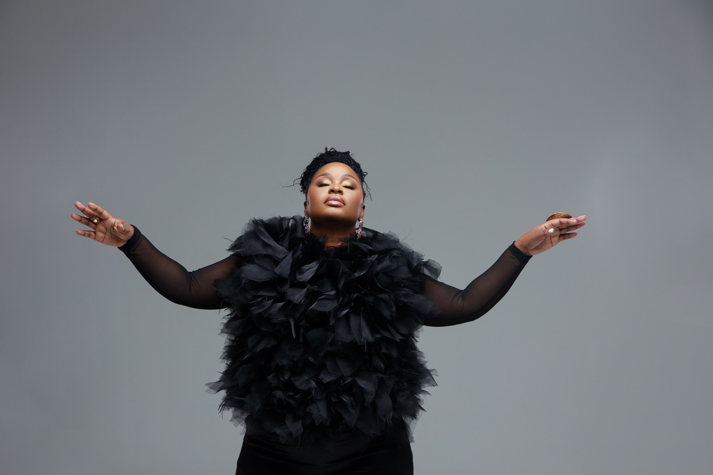 Xolly with arms outstretched in black studio styling